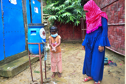 Halima and child using a hand-washing station