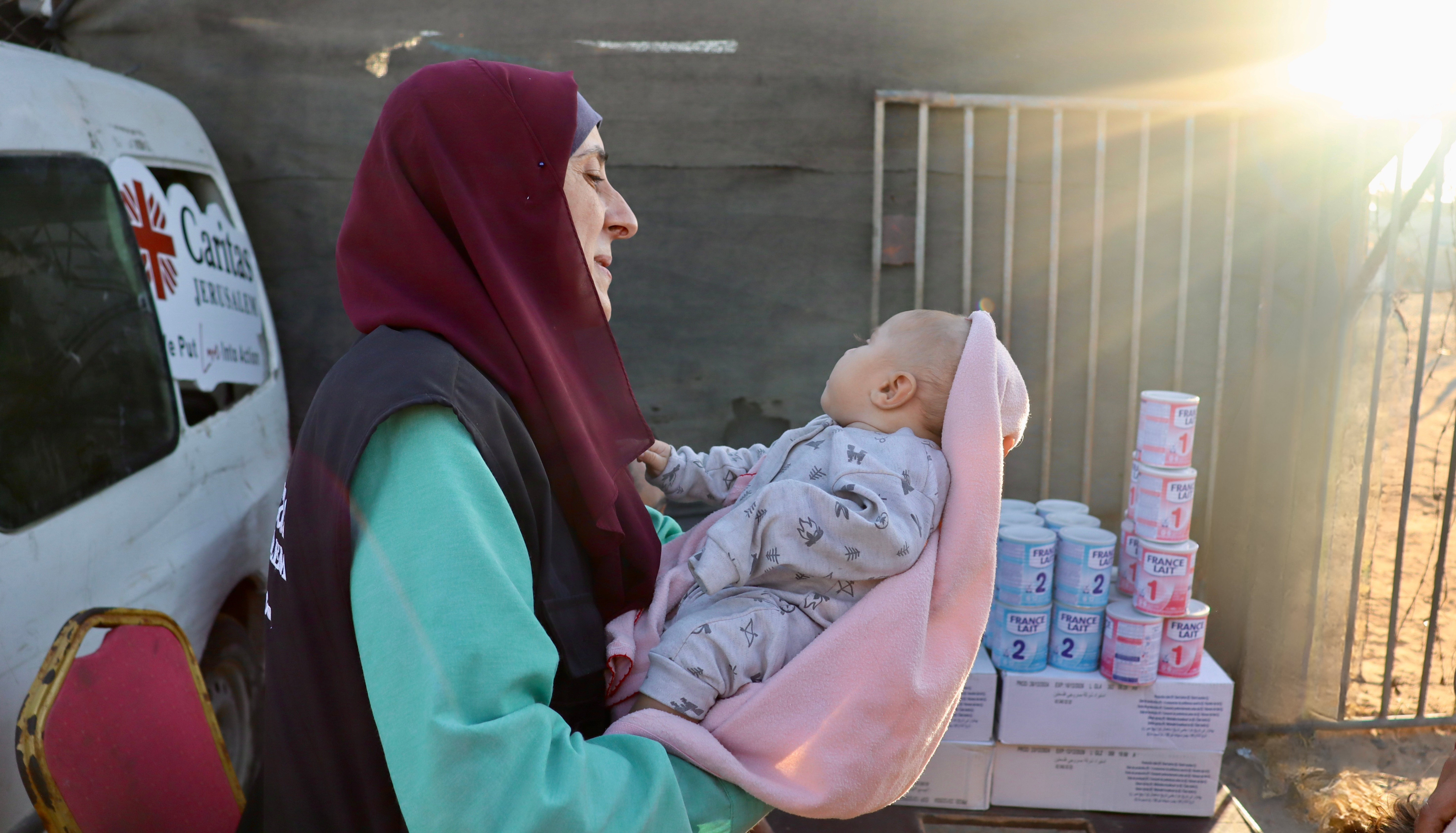 A Caritas Jerusalem Aid Worker Holds A Baby During Distribution Of Life Saving Formula Photo Credit Caritas Jerusalem