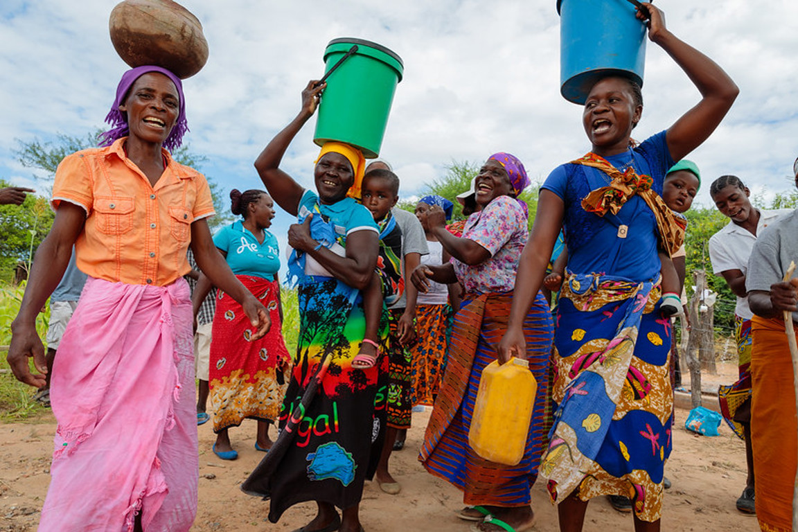 women living in poverty holding water on head