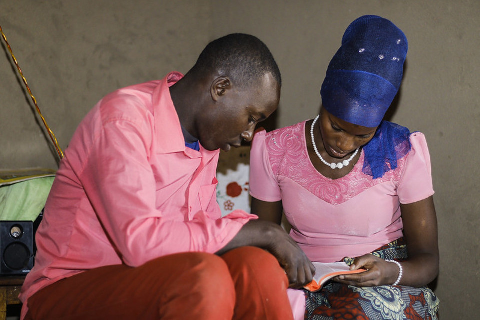 Olivia reads with her husband Thomas inside their home in Tanzania